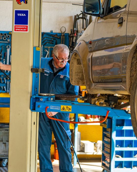 Meccanico al lavoro sul ponte sollevatore