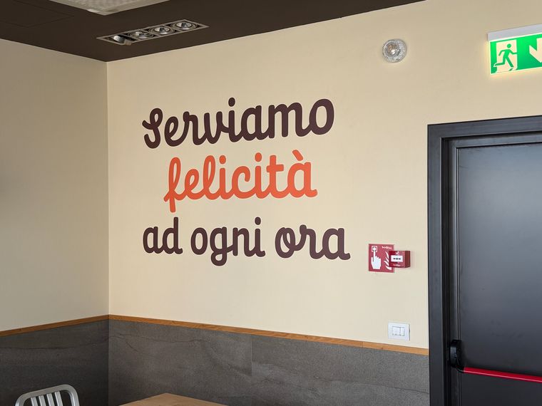 Scritta murale in vinile tagliato su parete di un ristorante